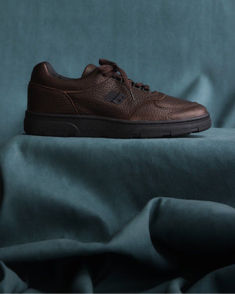 A New Balance Made in UK sneaker sitting in a flowing blue fabric studio backdrop. 