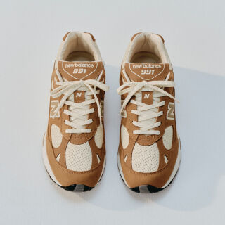 A pair of New Balance Made in UK sneakers sitting in a white studio environment. 