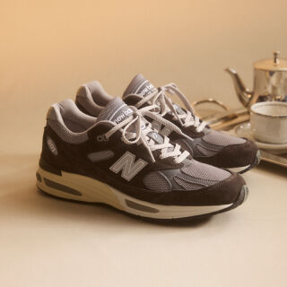 A pair of New Balance Made in UK sneakers in front of a rabbit in a brown textured studio environment. 
