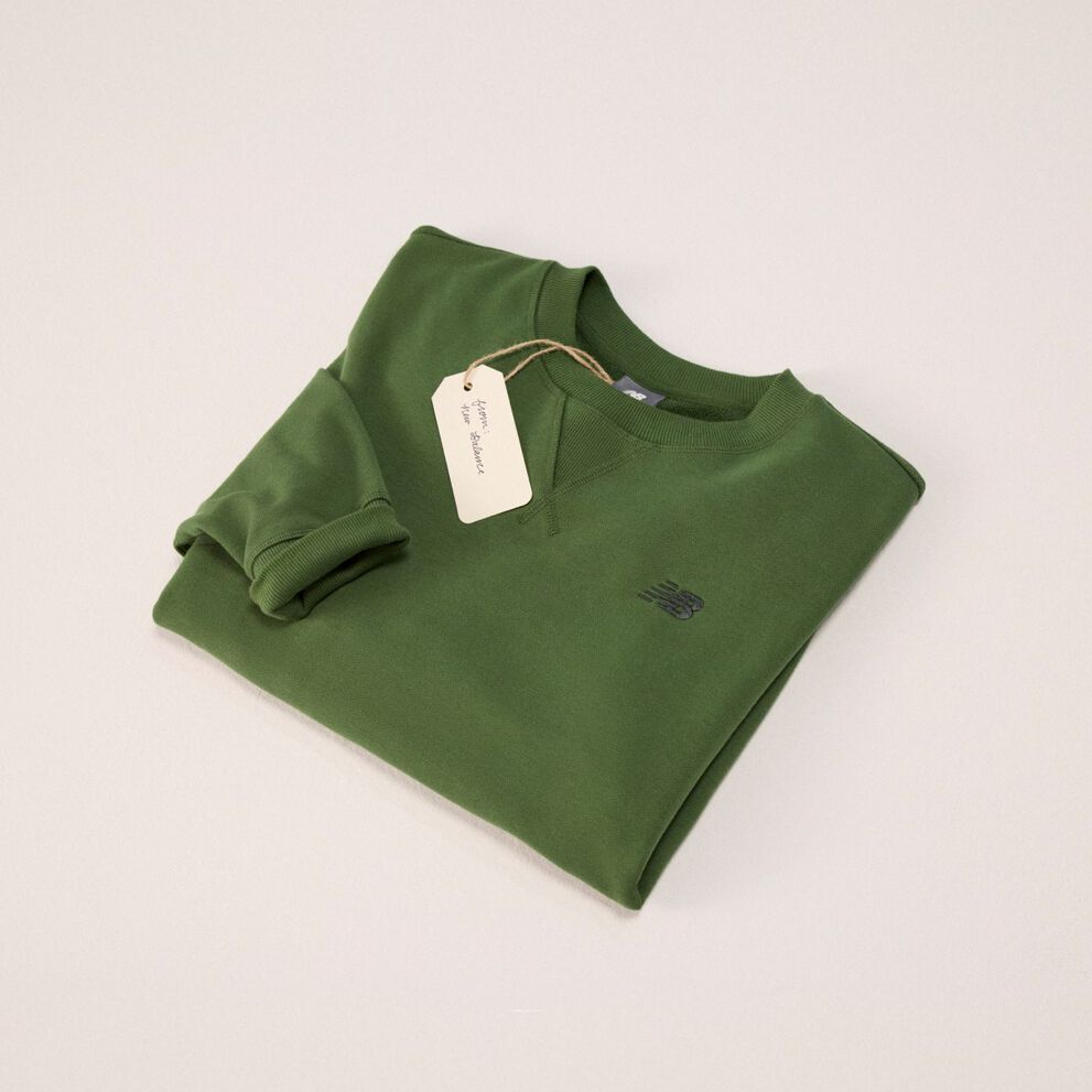Green sweatshirt folded into a square on a grey background.