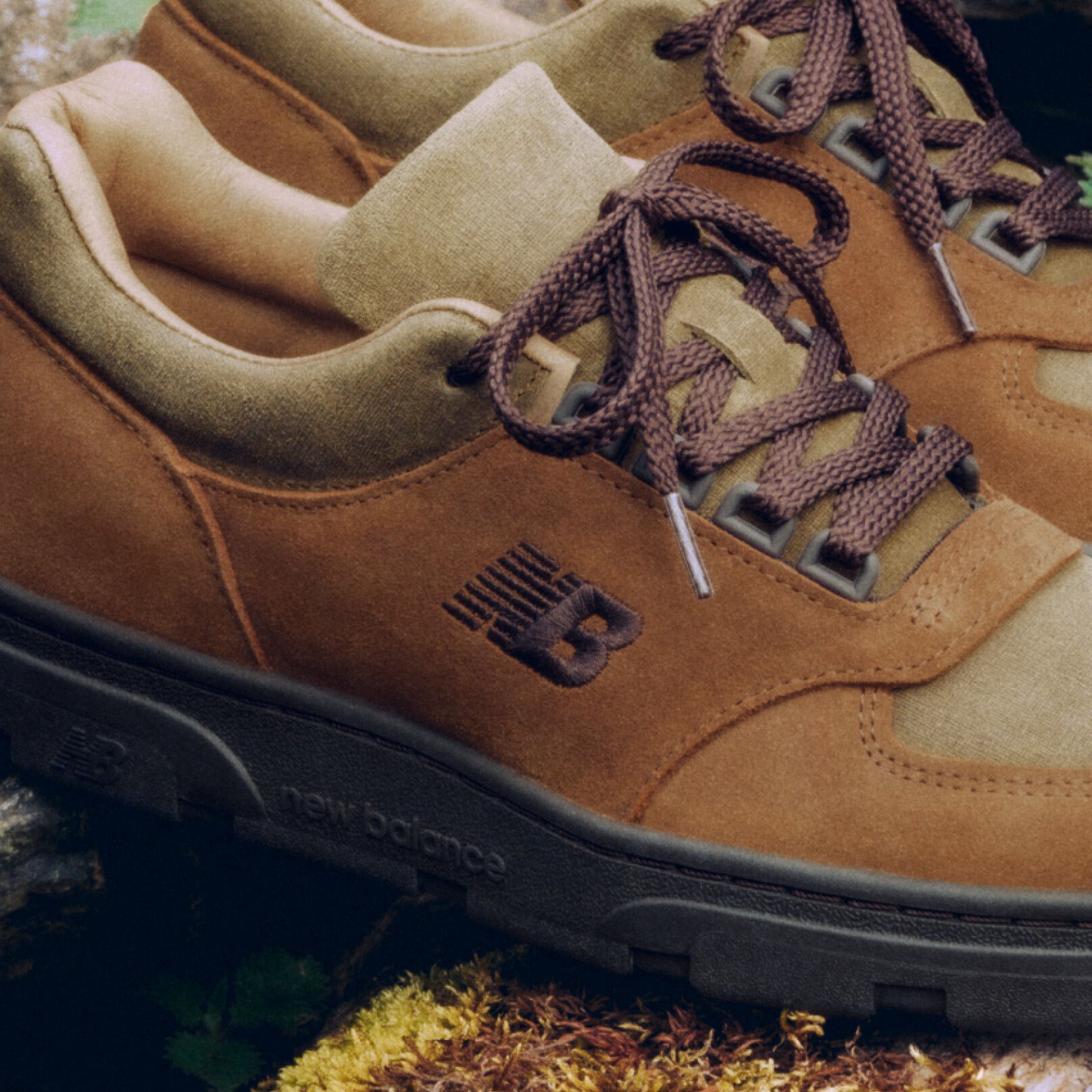 Detailed view of a pair of New Balance Made in UK sneakers sitting on a moss covered rock. 