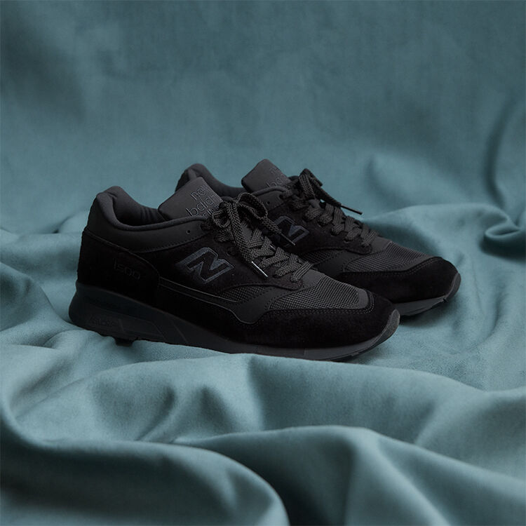 A pair of New Balance Made in UK sneakers on a flowing blue sheet backdrop.  
