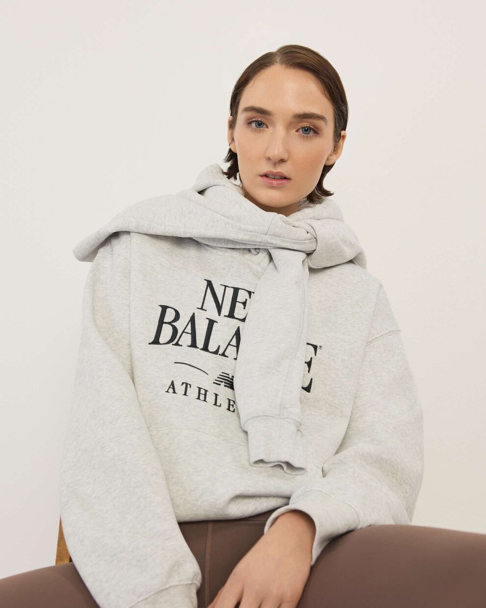 A woman wearing New Balance standing in front a white wall.